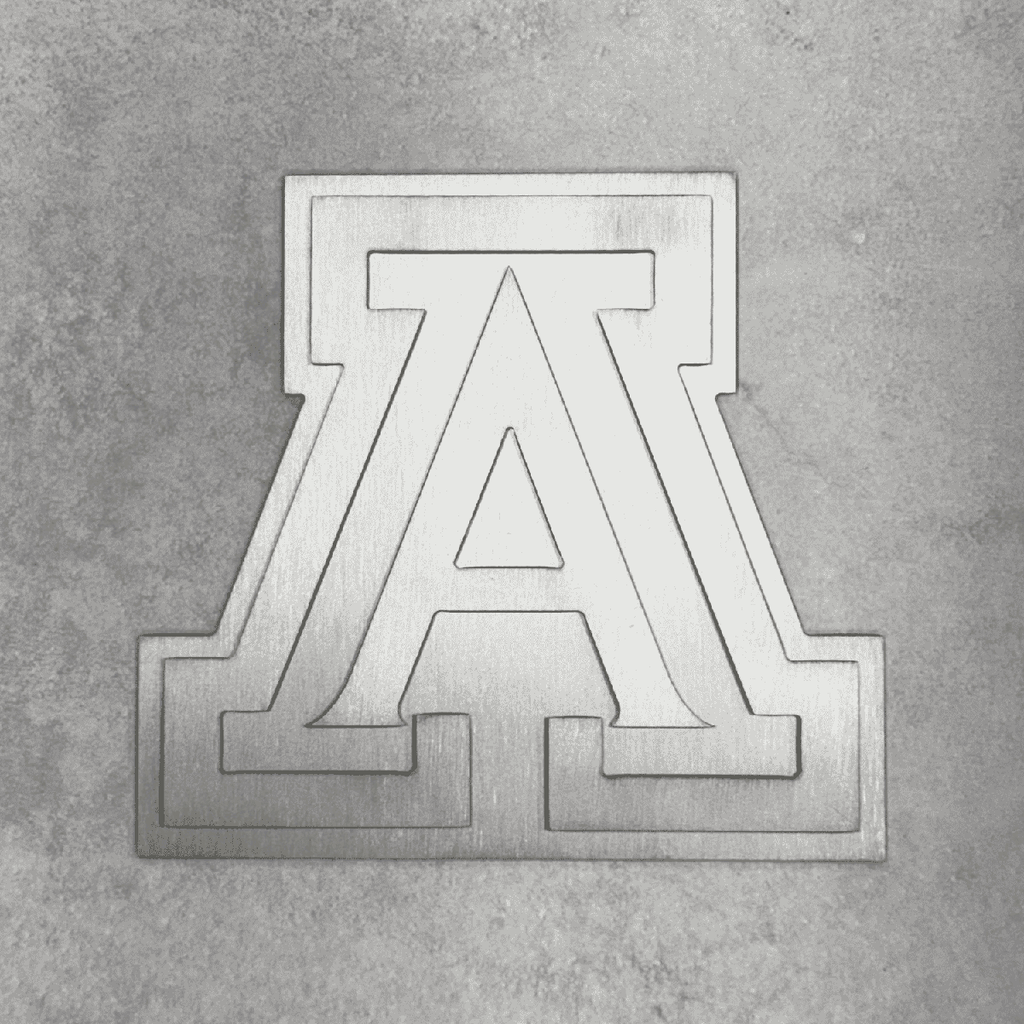 A brushed silver metal collegiate letter 'A' emblem, representing University of Arizona, mounted on a textured gray concrete wall.