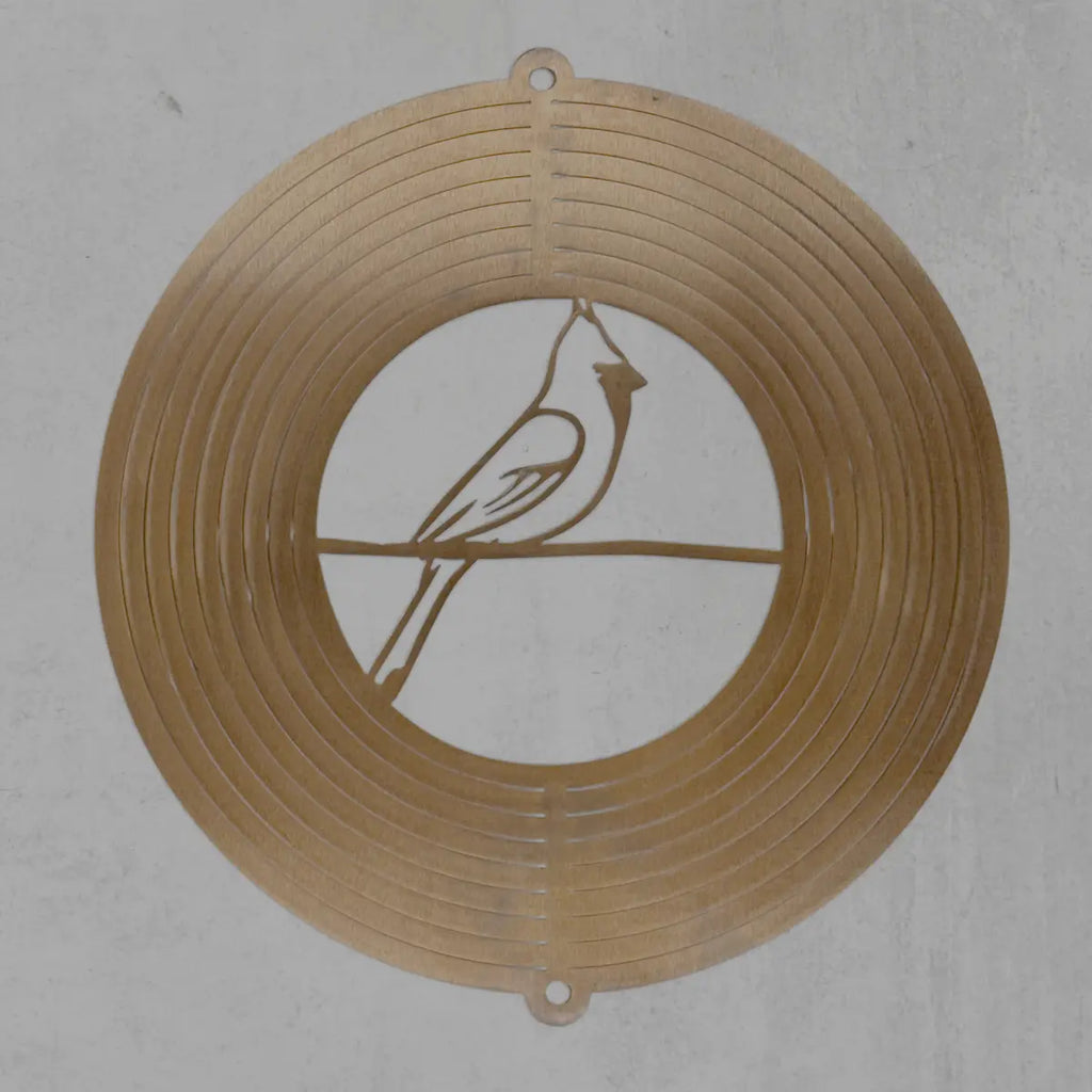 A circular metal wall art piece featuring a cardinal bird silhouette on a branch, displayed against a textured light gray background.