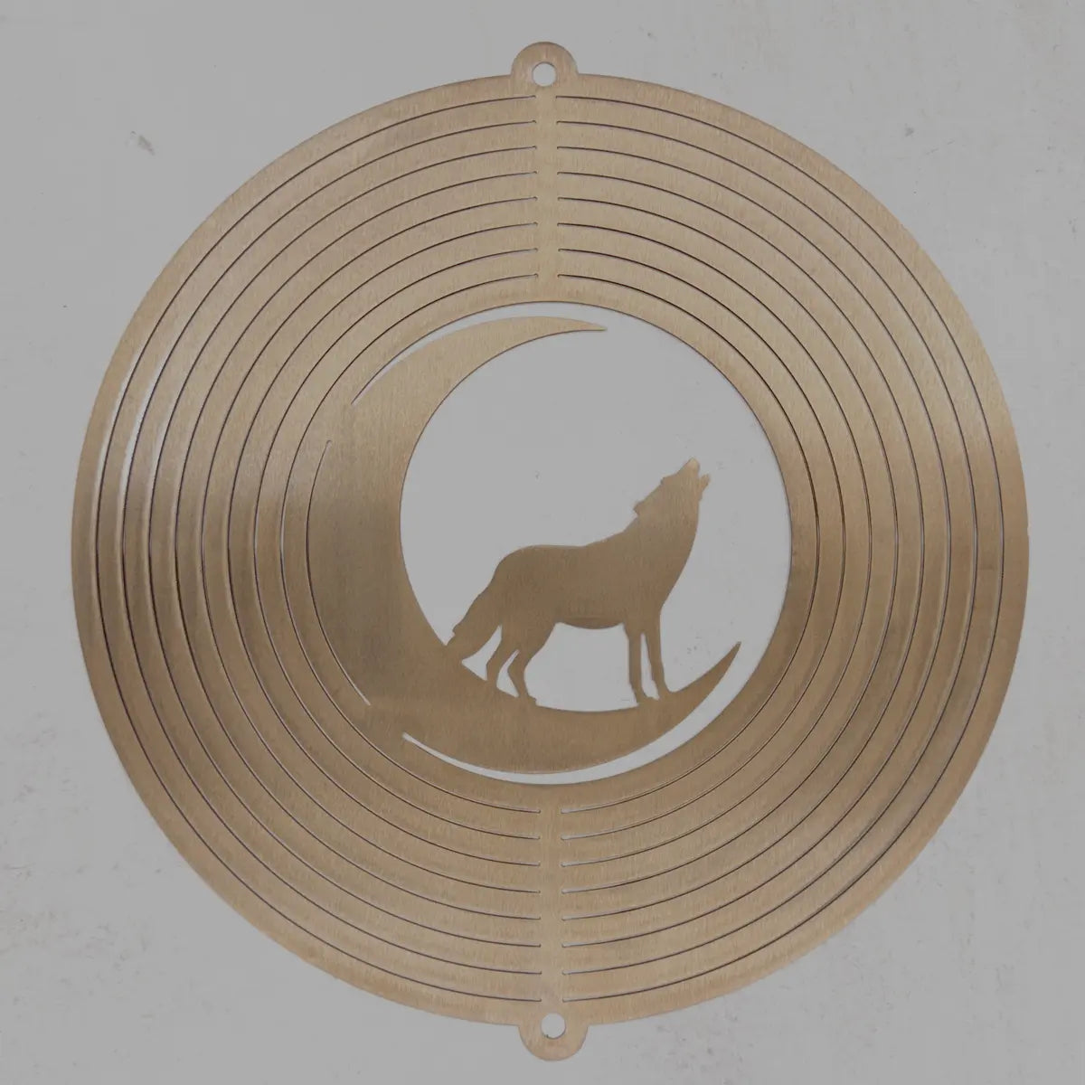 A circular metal wall art piece featuring concentric rings and a cutout silhouette of a howling coyote standing on a crescent moon, shown against a plain light background.