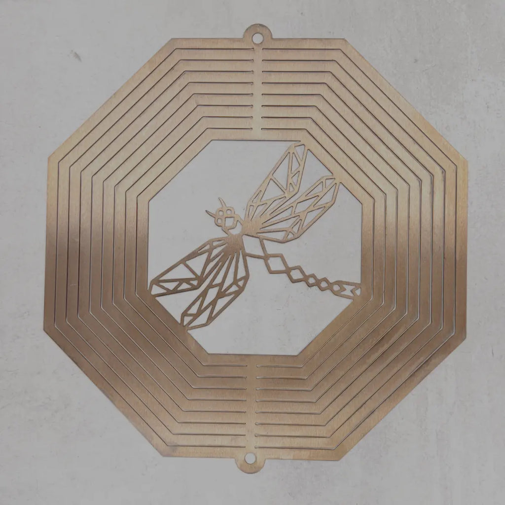 A square metal wall art piece with an octagonal border and a dragonfly cutout in the center, shown against a light gray textured background.