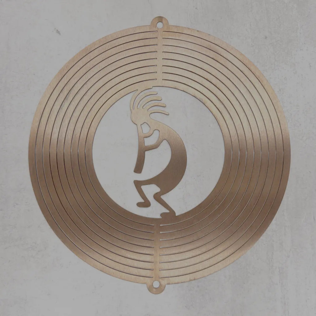 A circular metal wall art piece featuring concentric rings and a central Kokopelli silhouette cutout, displayed against a textured light gray wall.