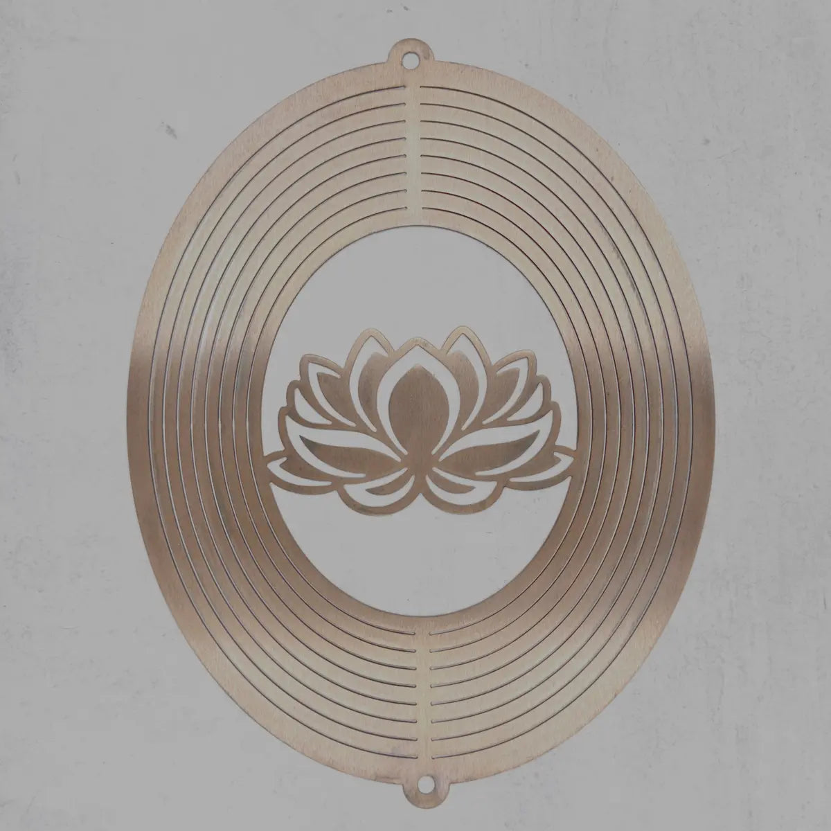 A circular metal wall art piece with concentric ring patterns and a lotus flower cutout in the center, shown against a textured gray background.