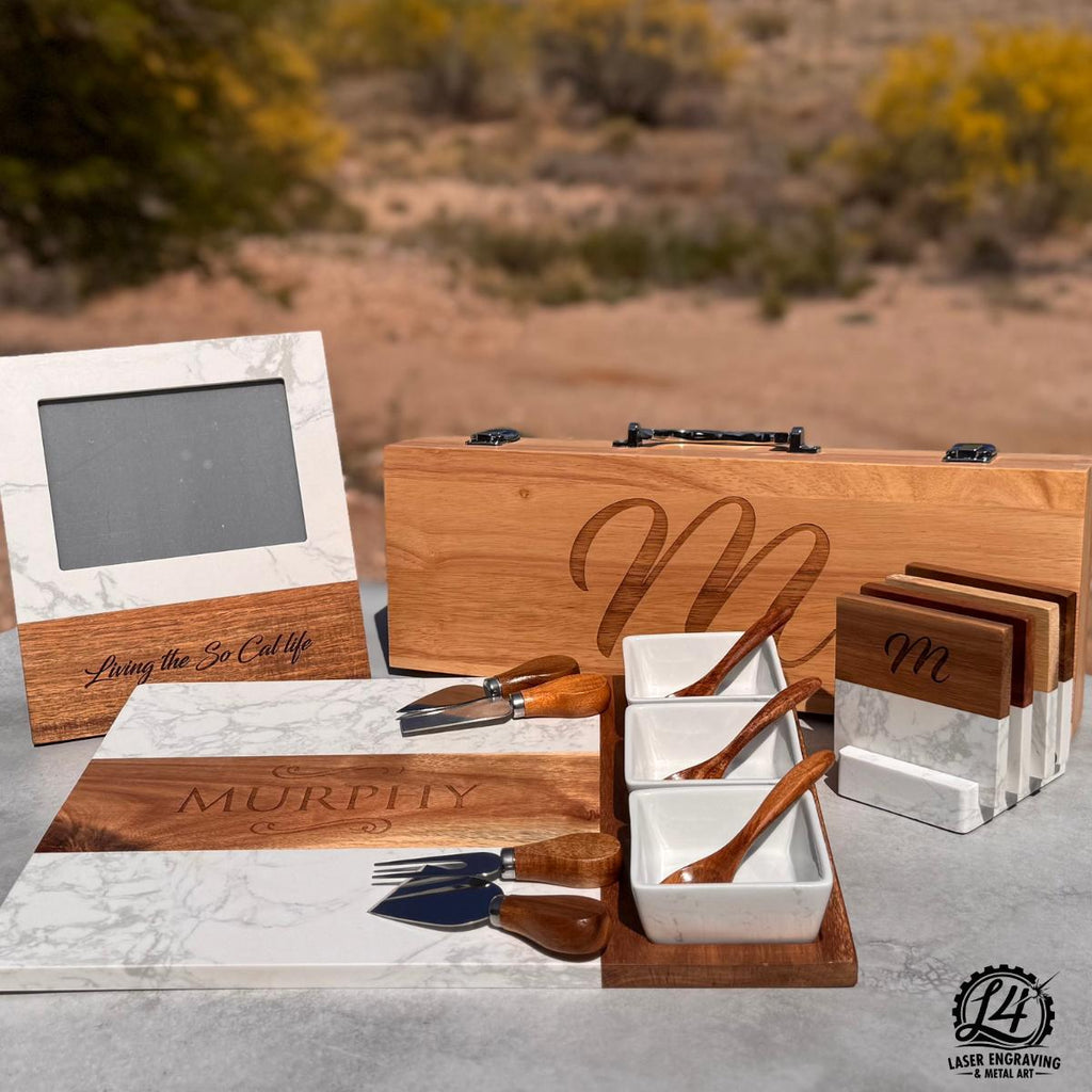 Custom engraved gift including charcuterie board with name, coasters with initial, picture frame, and engraved BBQ set.