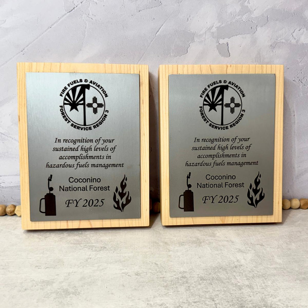 Two wooden plaques with engraved text and a logo on a metal surface. 