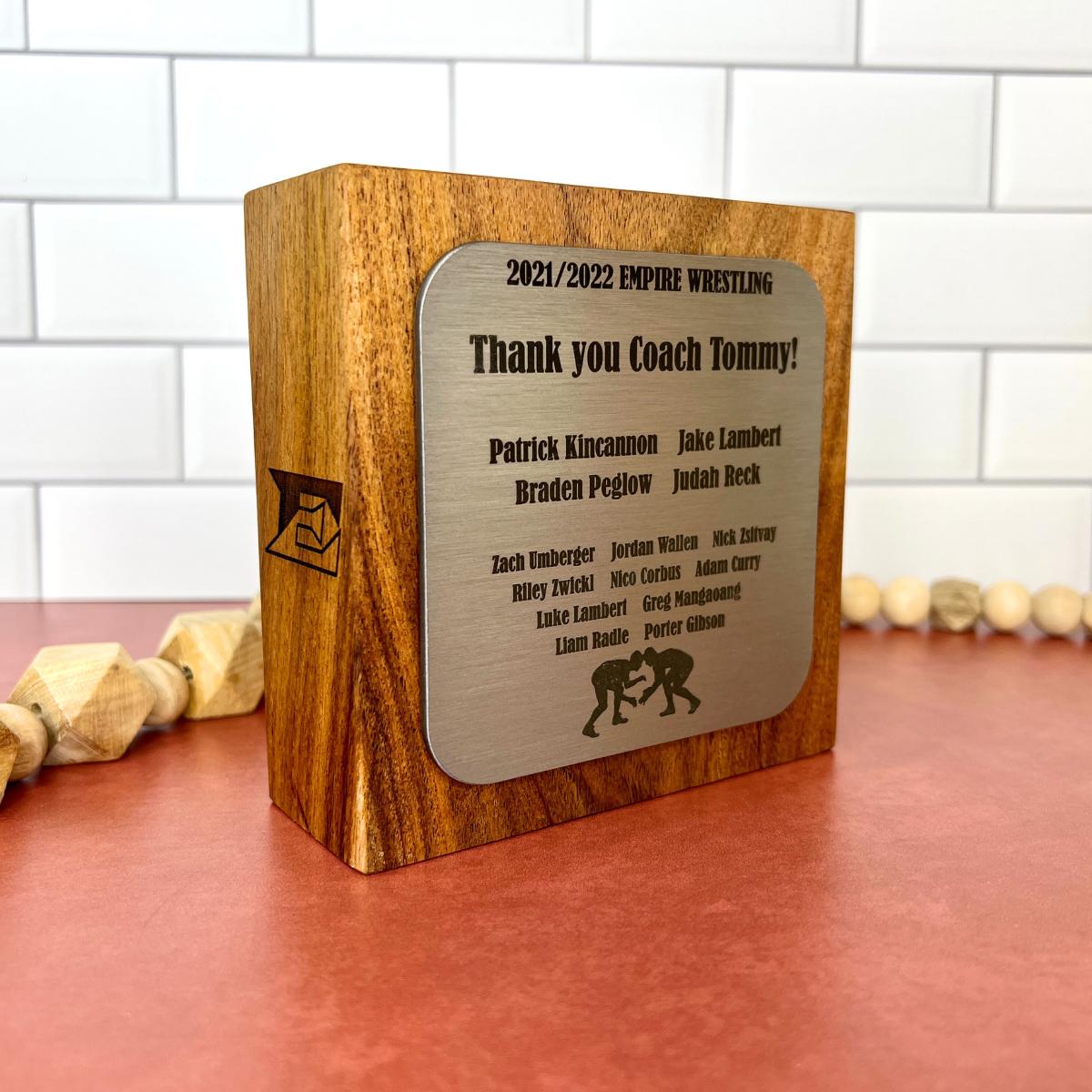 Metal and hardwood standing plaque with text on front and side. 