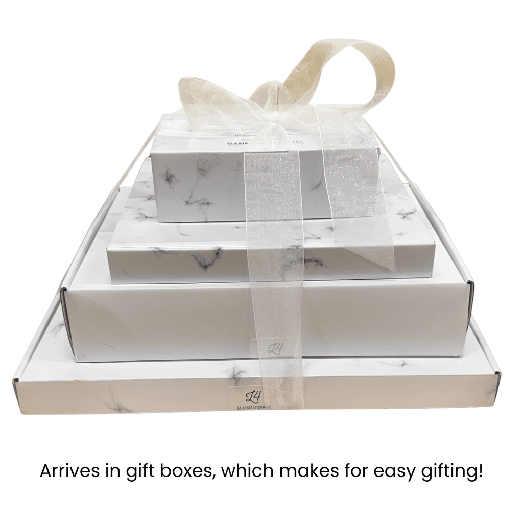 Four nested white and marble gift boxes, tied together with a sheer white ribbon, shown on a white background with the text 'Arrives in gift boxes, which makes for easy gifting!' below.