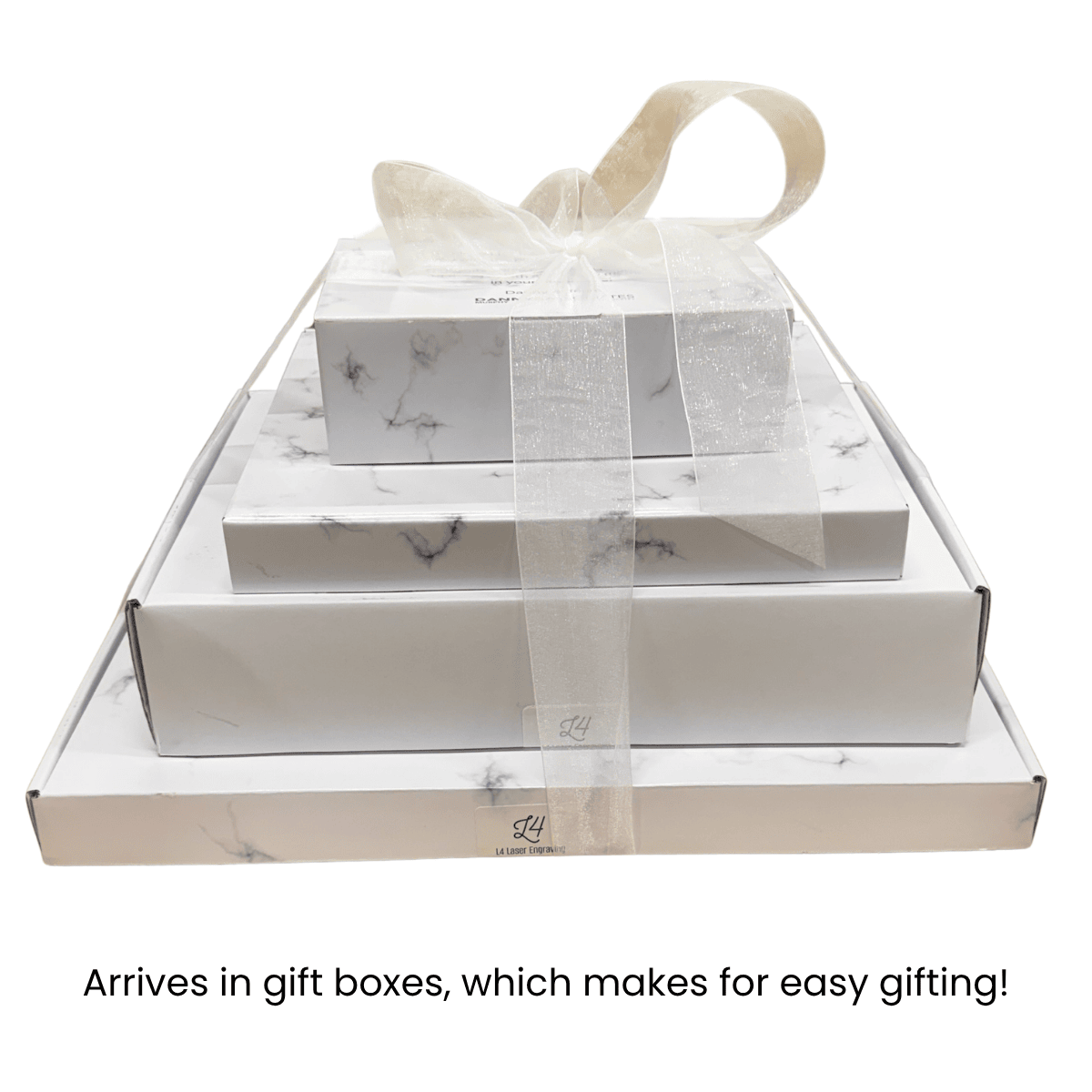 Four nested white and marble gift boxes, tied together with a sheer white ribbon, shown on a white background with the text 'Arrives in gift boxes, which makes for easy gifting!' below.