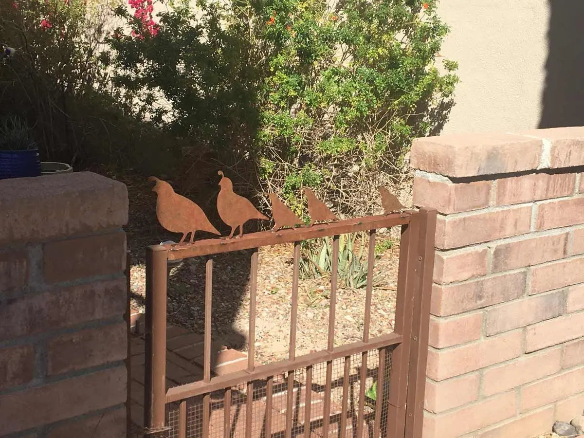 rusted metal quail on top of gate.
