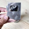 hand holding a small raw metal bottle opener