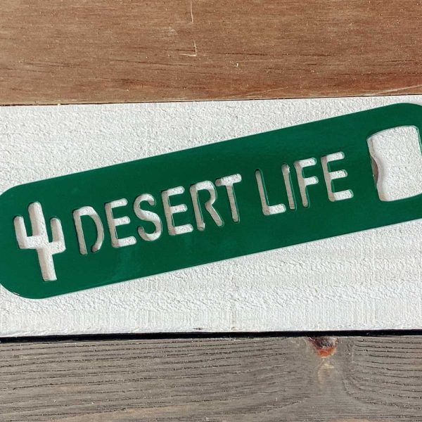 close up of green plasma cut bottle opener that says Desert Life