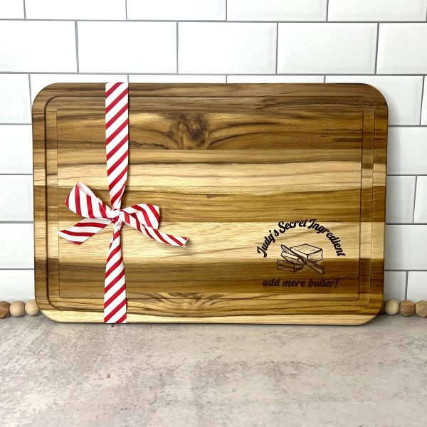engraved acacia cutting board with red and white striped ribbon tied around it