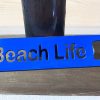 Beach life bottle opener in blue leaned against a bottle