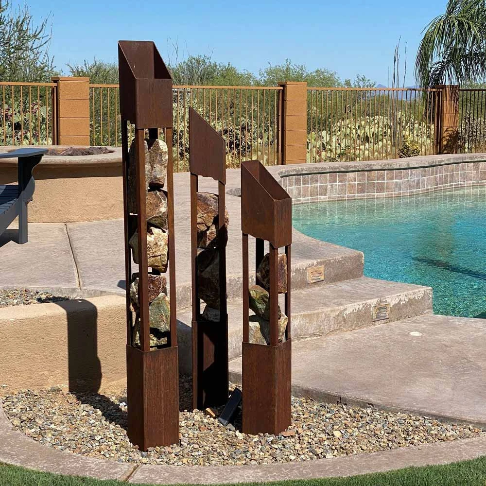 Three metal torches with rocks inside next to pool.