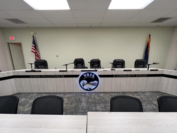 image shows an empty board room with metal strip signs as well as a round lighted metal sign.