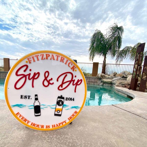 Sip & Dip acrylic sign in front of a pool