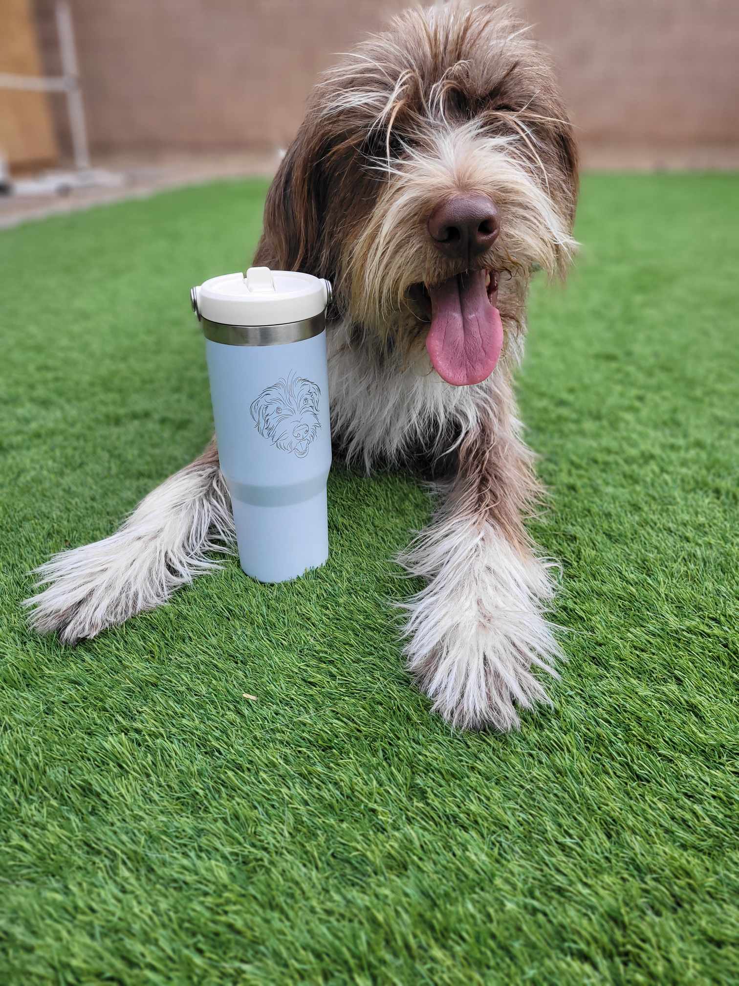Cute dog next to a Stanley tumbler engraved with his face.