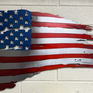 red, white, and blue tattered metal flag on a white brick wall