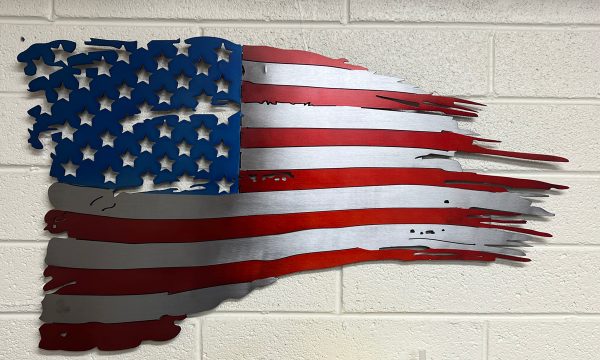 red, white, and blue tattered metal flag on a white brick wall