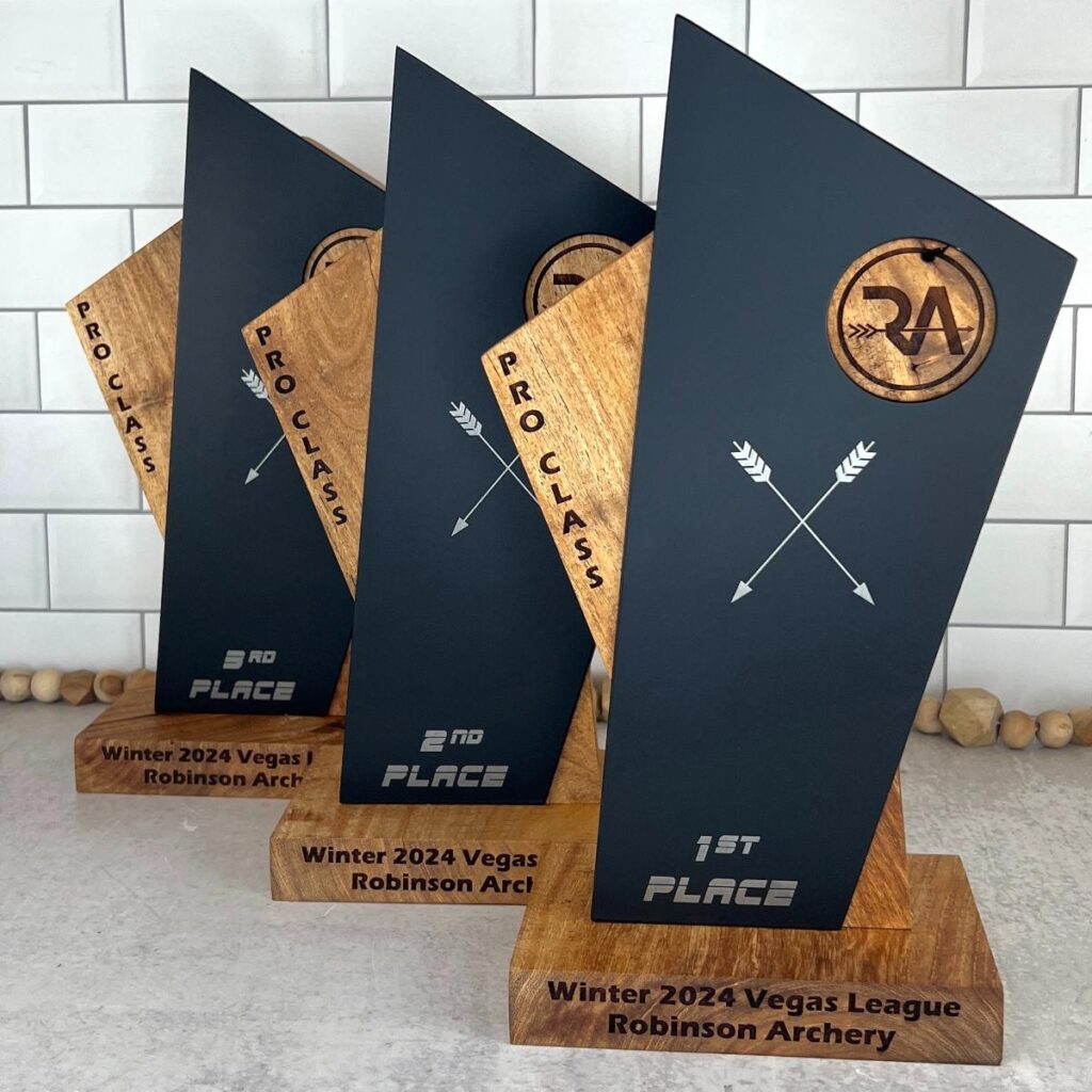 Three mesquite wood and metal awards for archery tournament.